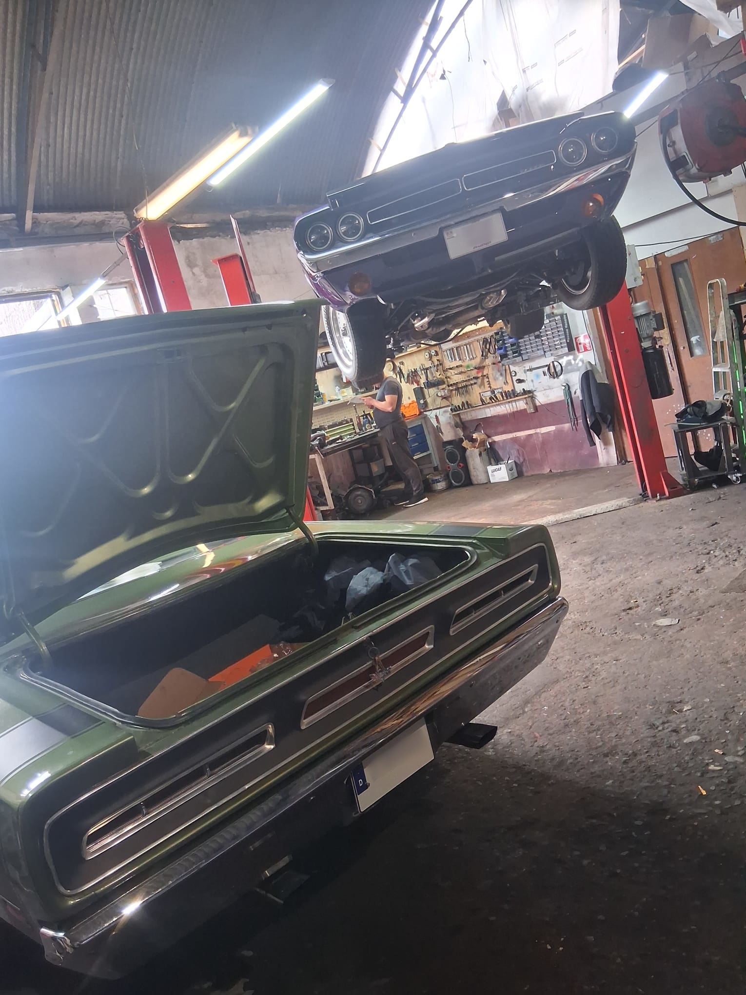 Inside the Toms Motorworks garage — a classic on the lift and another up on the bench
